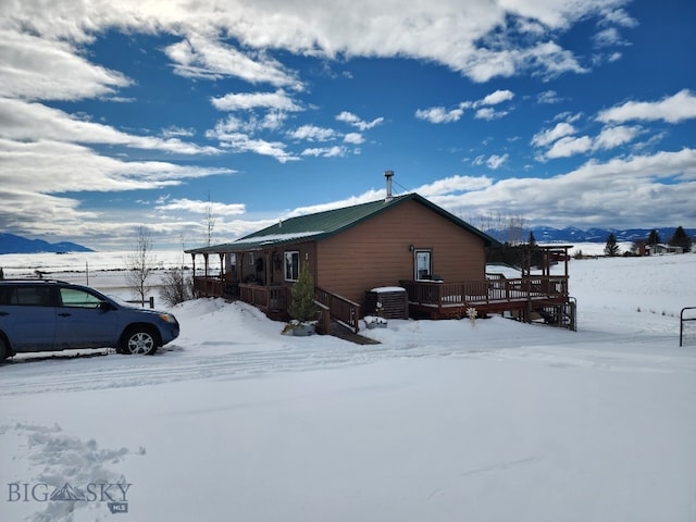 snow covered property with a deck with mountain view