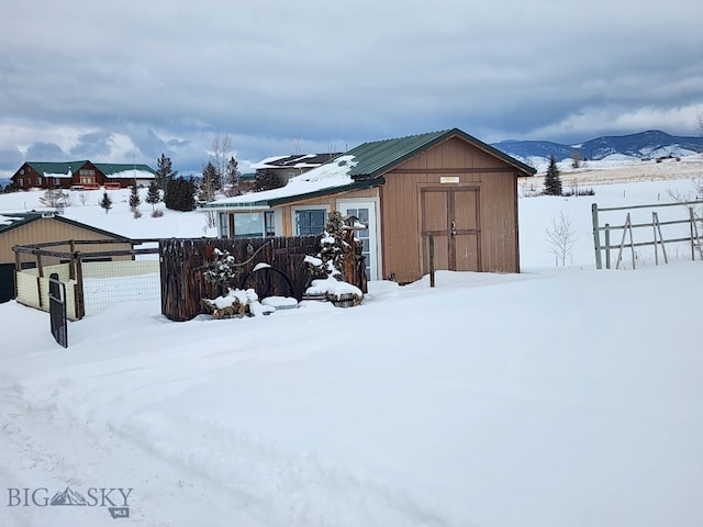 snow covered structure with fence and a mountain view