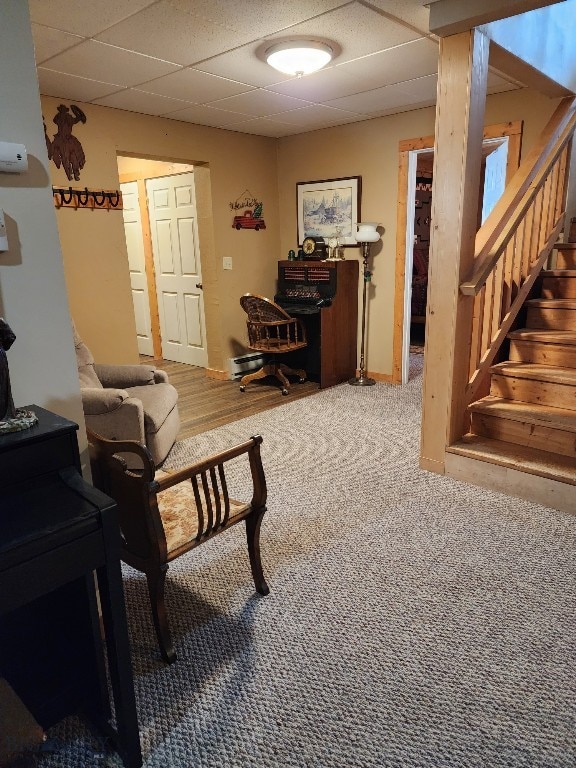 carpeted living area with a paneled ceiling and stairs