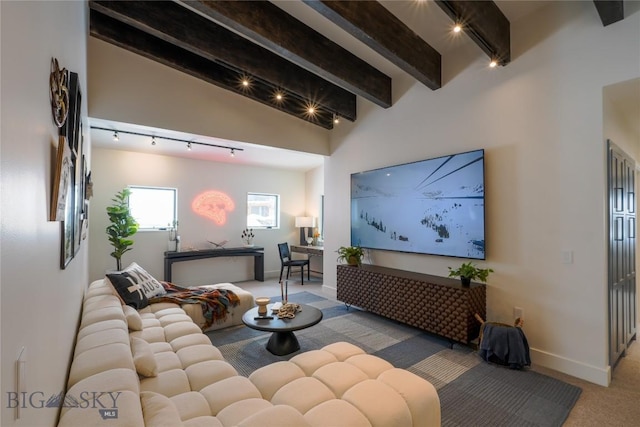 carpeted living area featuring rail lighting, beamed ceiling, and baseboards