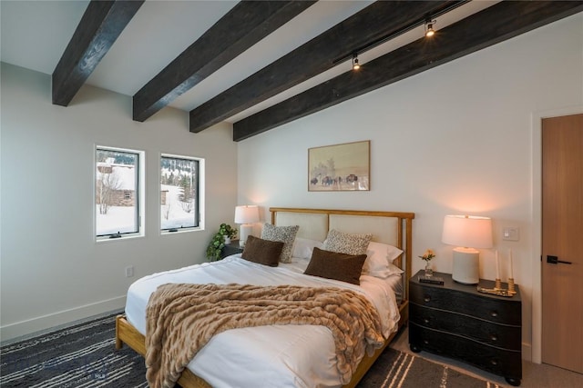 bedroom featuring rail lighting, vaulted ceiling with beams, and baseboards