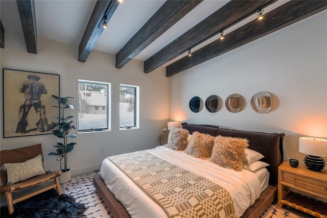 bedroom featuring rail lighting, baseboards, and beam ceiling