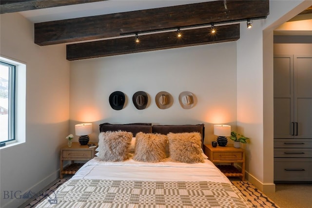 bedroom with track lighting, beam ceiling, and baseboards