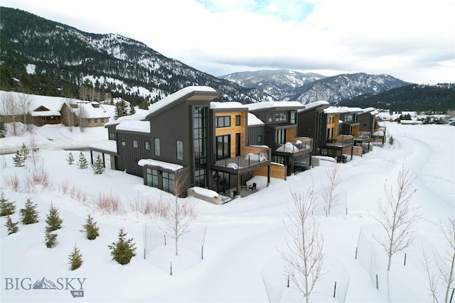 snow covered rear of property featuring a mountain view