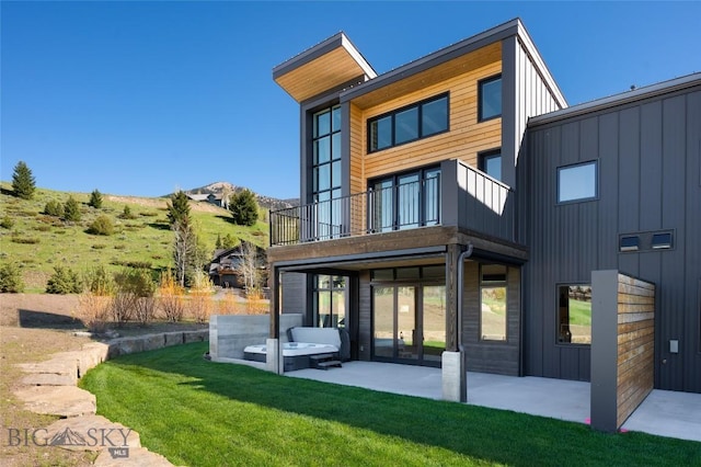 back of property featuring a lawn, a patio, board and batten siding, and a balcony