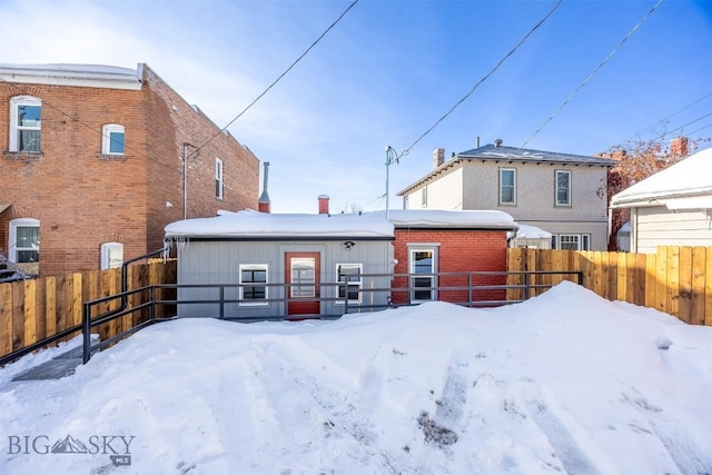 snow covered property featuring a fenced backyard and brick siding