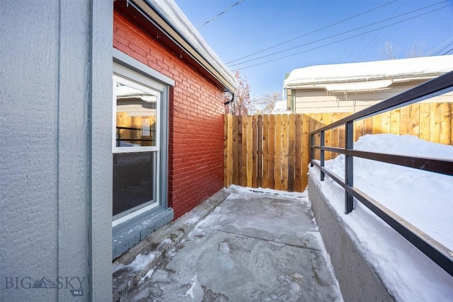 snow covered patio featuring fence