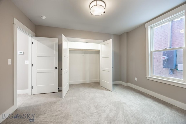 unfurnished bedroom featuring a closet, light carpet, and baseboards