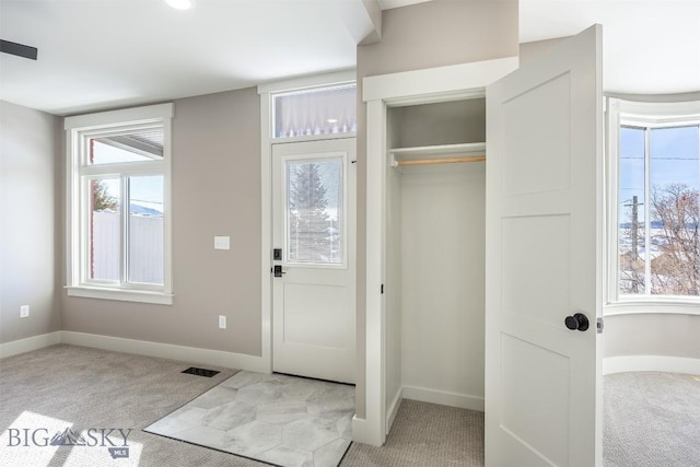 entrance foyer featuring baseboards, a wealth of natural light, and light colored carpet