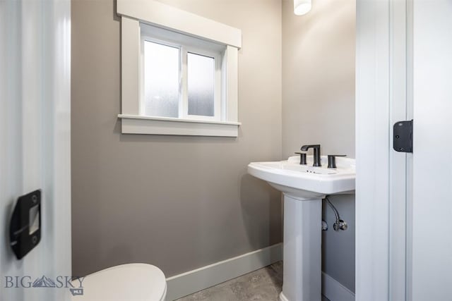 bathroom featuring toilet, baseboards, and a sink