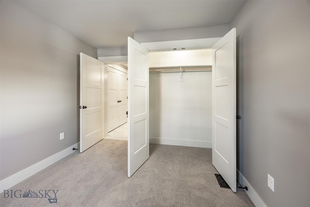 unfurnished bedroom with baseboards, a closet, and light colored carpet