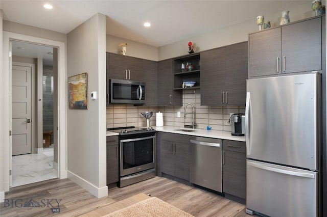 kitchen featuring a sink, light countertops, appliances with stainless steel finishes, open shelves, and tasteful backsplash