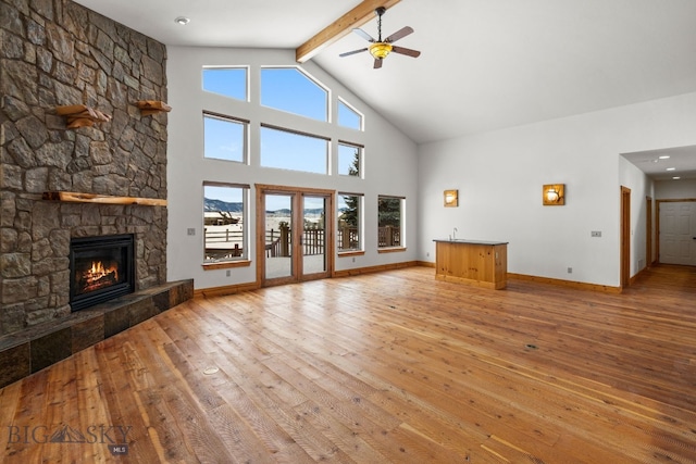 unfurnished living room with ceiling fan, a fireplace, hardwood / wood-style flooring, and baseboards