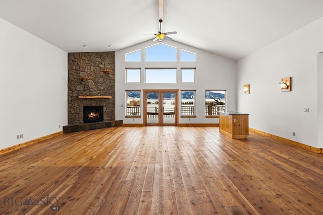 unfurnished living room with baseboards, a fireplace, high vaulted ceiling, and hardwood / wood-style floors