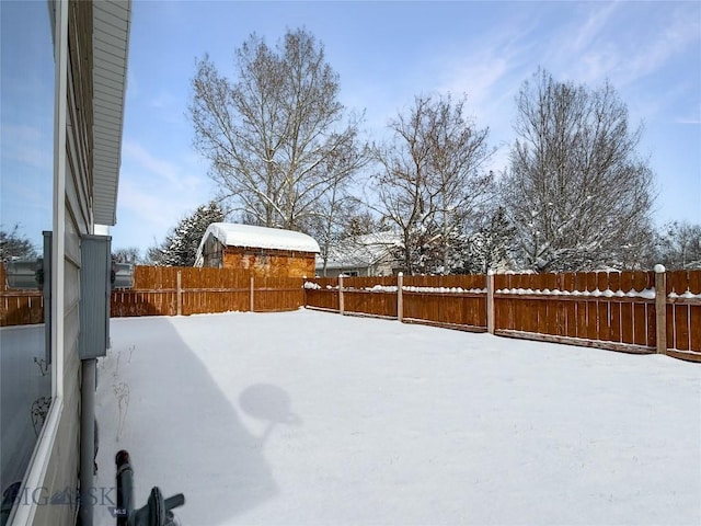 snowy yard with a fenced backyard