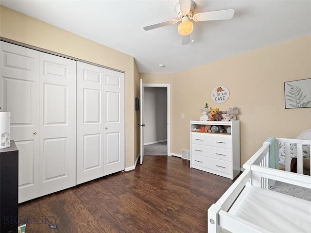 bedroom featuring dark wood-style floors, a closet, visible vents, a ceiling fan, and a nursery area