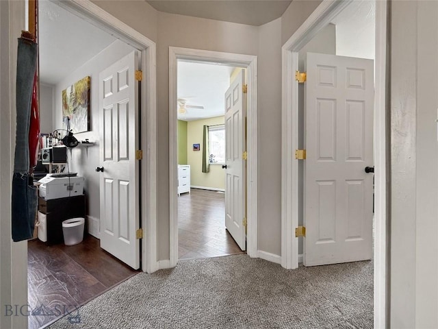 hall with baseboards and dark colored carpet