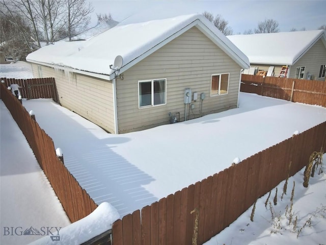 snow covered back of property featuring fence