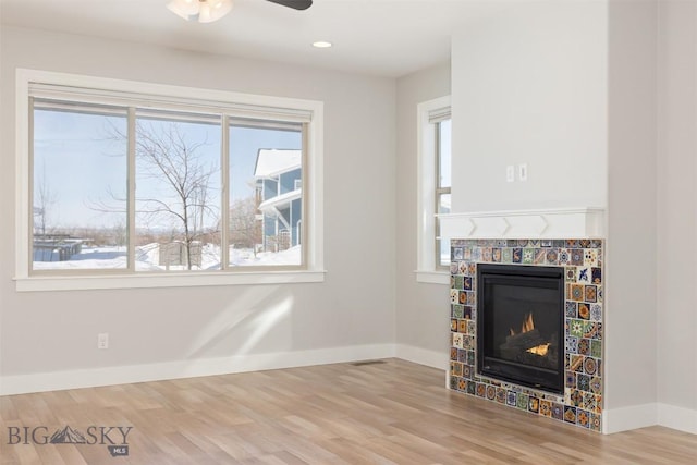 500 Westgate, Bozeman, MT 59718 - unfurnished living room featuring a tiled fireplace, wood finished floors, a ceiling fan, and baseboards