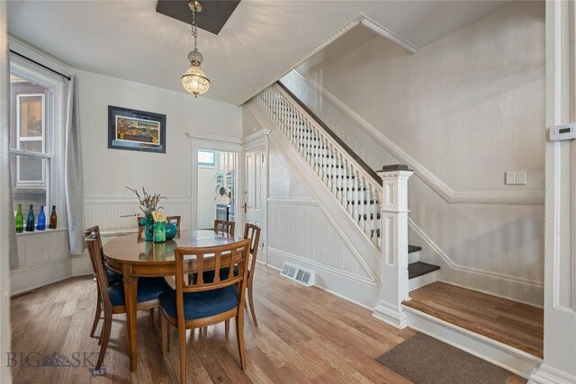 dining area featuring stairs, a wainscoted wall, wood finished floors, and visible vents