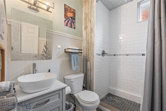 full bath featuring wainscoting, a shower stall, toilet, and vanity