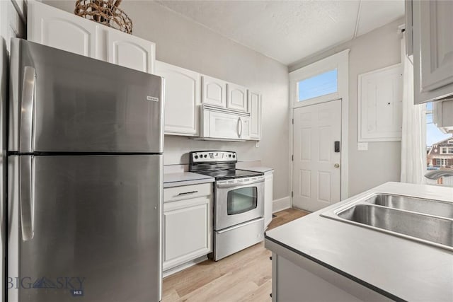 kitchen with stainless steel appliances, a sink, light countertops, and white cabinets
