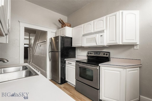 kitchen featuring stainless steel appliances, white cabinetry, and a sink