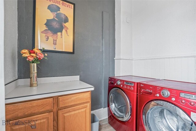 clothes washing area featuring washer and clothes dryer, wainscoting, and cabinet space