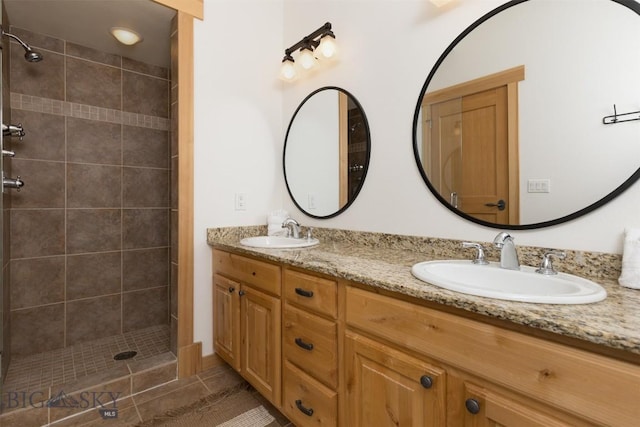 full bathroom featuring double vanity, a stall shower, a sink, and tile patterned floors