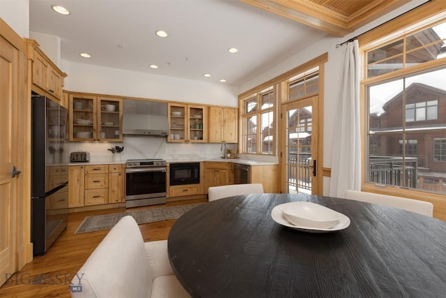 kitchen with wood finished floors, light countertops, appliances with stainless steel finishes, and wall chimney range hood