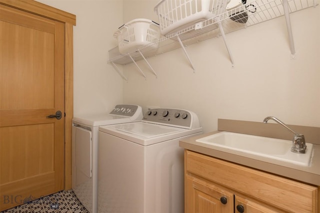 clothes washing area with cabinet space, washer and dryer, and a sink