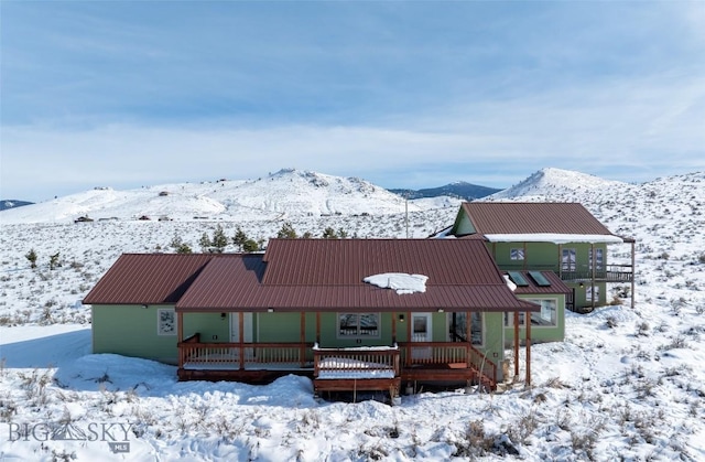 snow covered property with a mountain view and metal roof