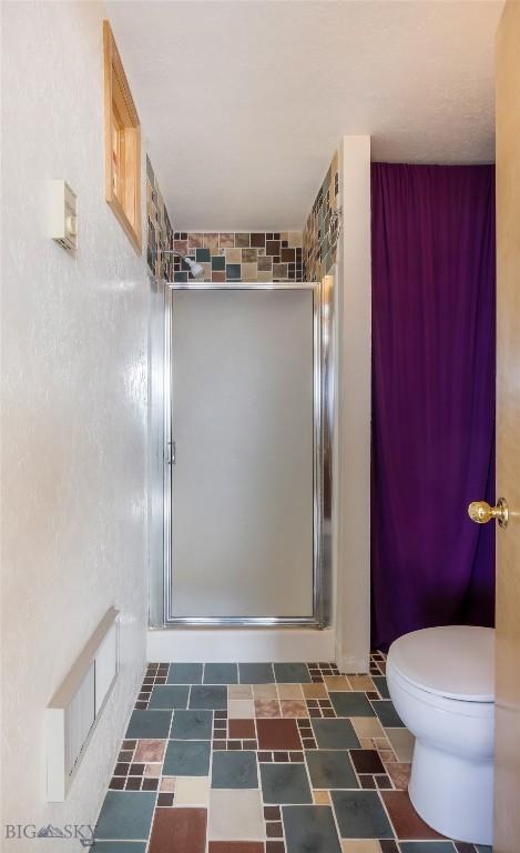 bathroom featuring a shower stall and toilet