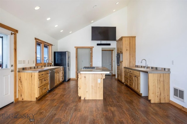 kitchen featuring visible vents, stainless steel countertops, a kitchen island, appliances with stainless steel finishes, and a sink