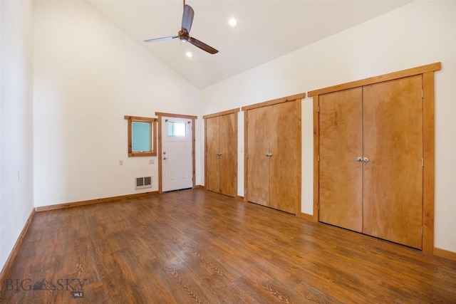 unfurnished bedroom featuring high vaulted ceiling, wood finished floors, visible vents, baseboards, and multiple closets