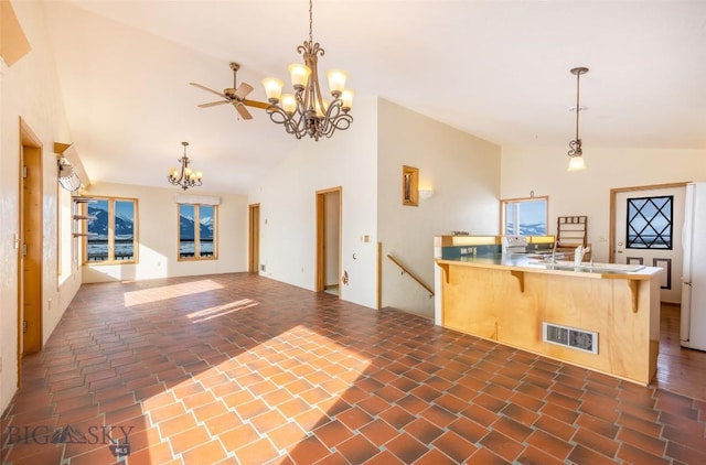 kitchen featuring decorative light fixtures, visible vents, open floor plan, a sink, and a peninsula