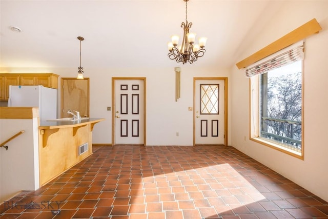 kitchen with visible vents, a kitchen bar, freestanding refrigerator, and pendant lighting