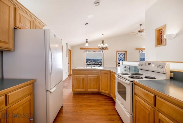 kitchen with dark countertops, hanging light fixtures, light wood-style flooring, vaulted ceiling, and white appliances