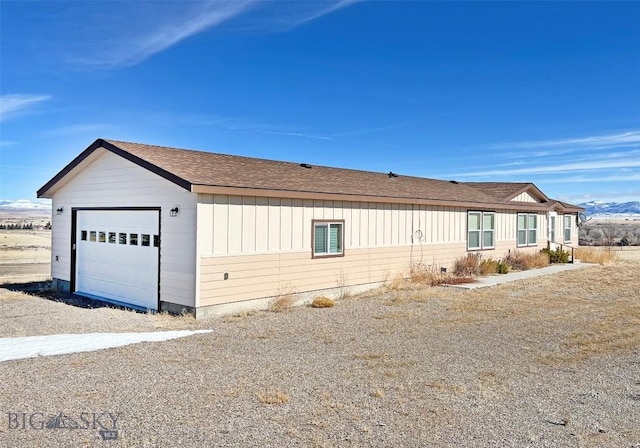 view of front of property featuring an attached garage, board and batten siding, and roof with shingles