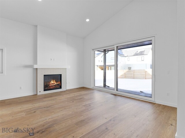 2820 S 30th Ave, Bozeman, MT 59718 - unfurnished living room with a warm lit fireplace, light wood-style floors, high vaulted ceiling, baseboards, and recessed lighting