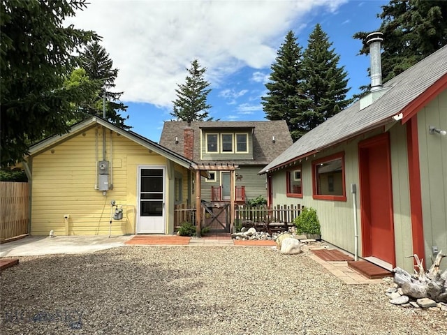 rear view of property with a gate, a patio area, fence, and a chimney