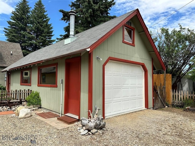 detached garage with gravel driveway and fence