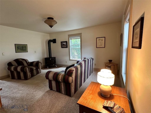 carpeted living room with a wood stove and baseboards