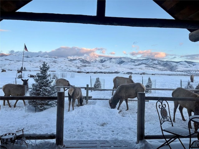 yard covered in snow featuring a mountain view and a balcony