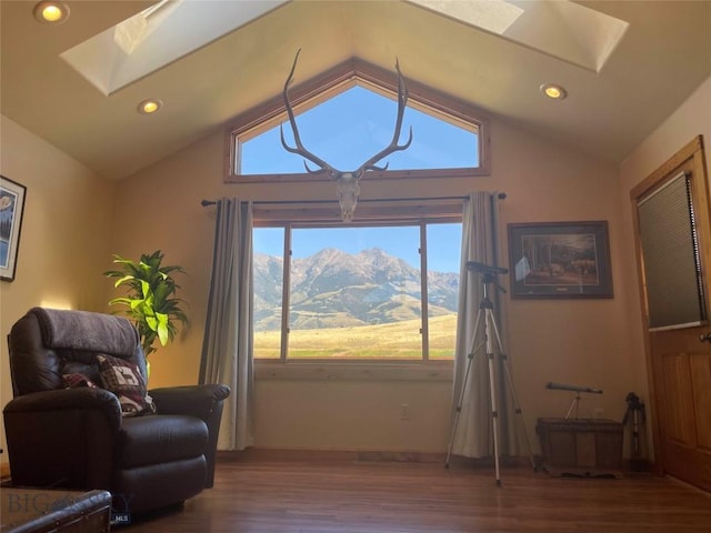 living area featuring lofted ceiling with skylight, a mountain view, wood finished floors, and recessed lighting