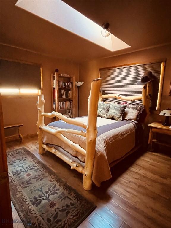 bedroom with a skylight and wood finished floors