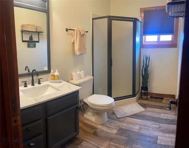 full bathroom with wood finish floors, toilet, vanity, and a shower stall