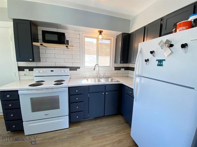 kitchen with white appliances, decorative backsplash, light wood-style flooring, light countertops, and a sink