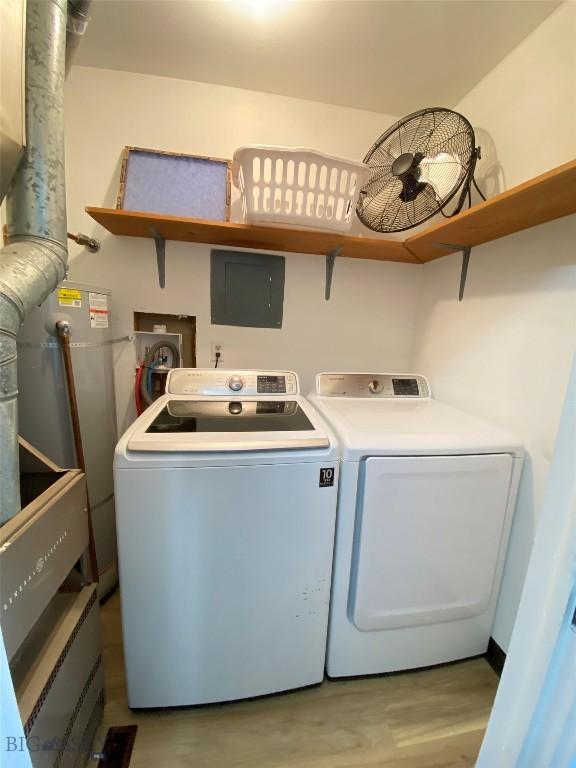 clothes washing area with laundry area, water heater, light wood finished floors, and washing machine and clothes dryer