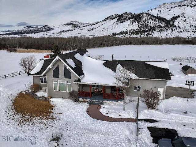 snow covered house featuring a mountain view and a porch